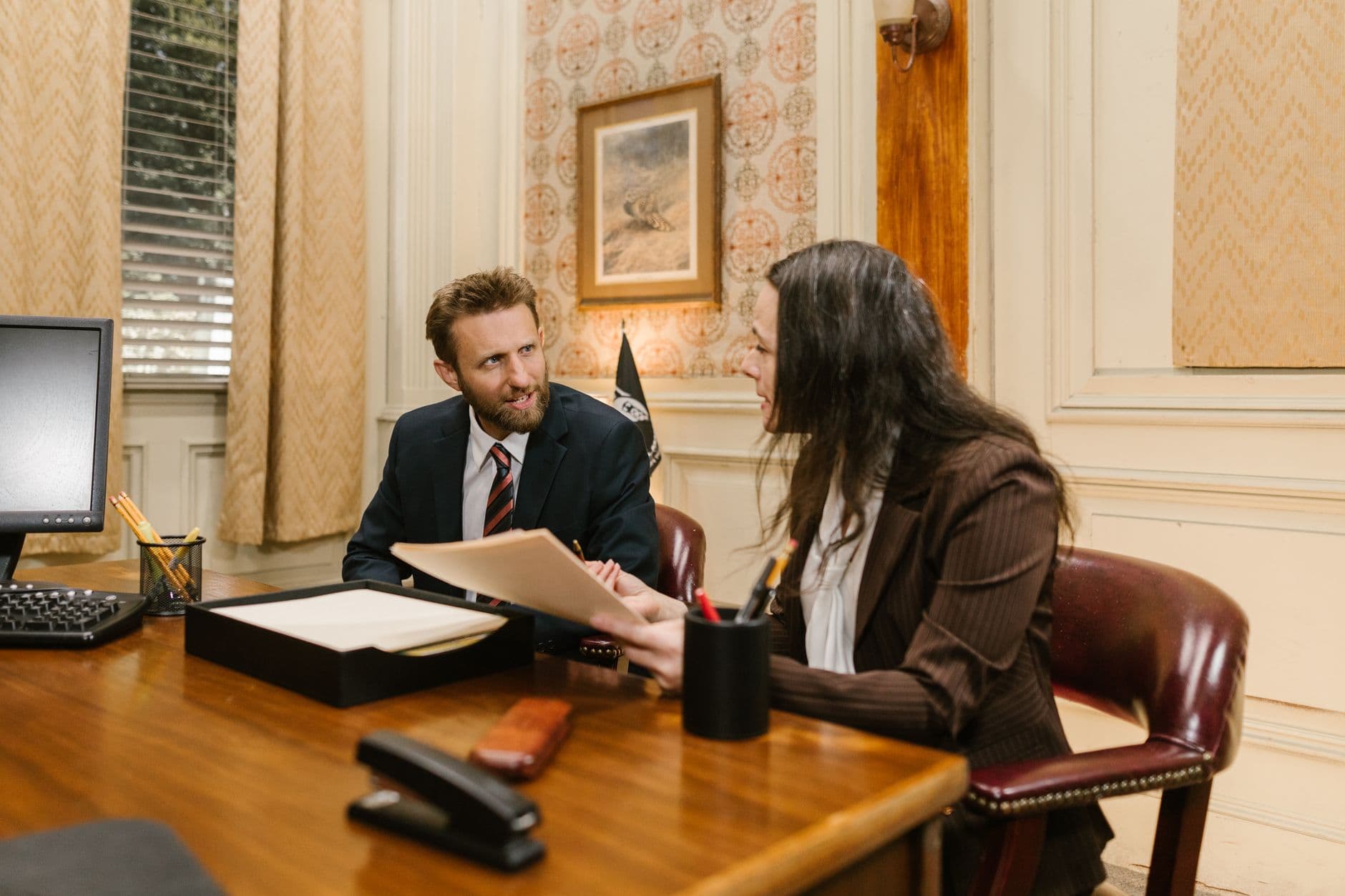 Two professionals reviewing official documents across an office desk